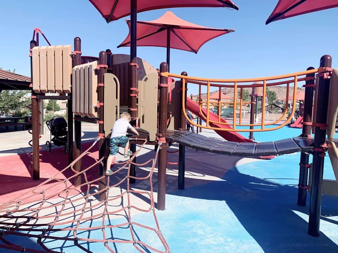 Child climbing the spider web in between parks