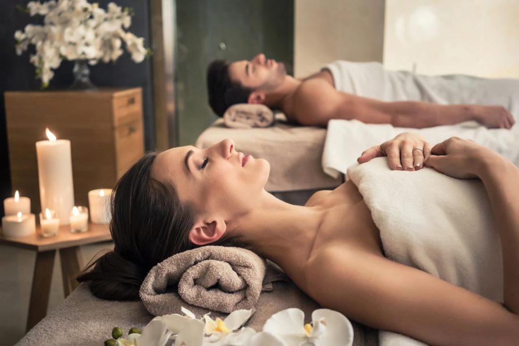 Young man and woman lying down on massage beds at Asian luxury spa and wellness centre